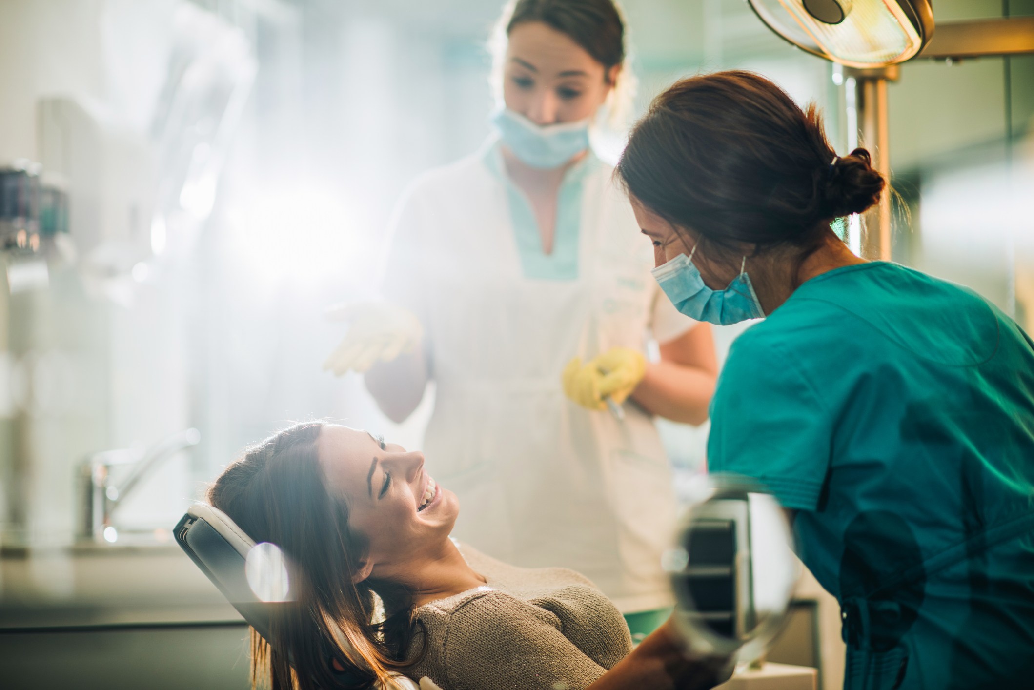 Mujer sonriente sentada en la silla del dentista y hablando con su dentista antes del examen dental.