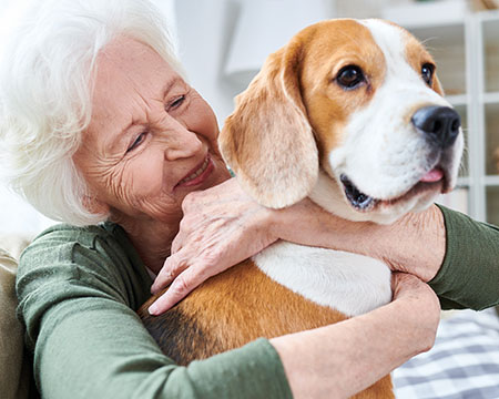 mujer mayor abrazando a su perro y sonriendo