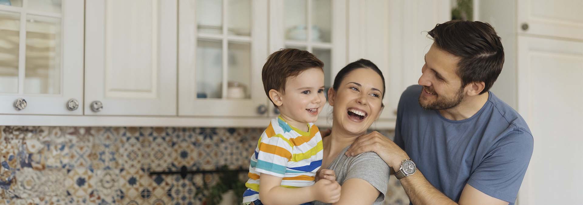una pareja joven y su hijo sonríen en la cocina