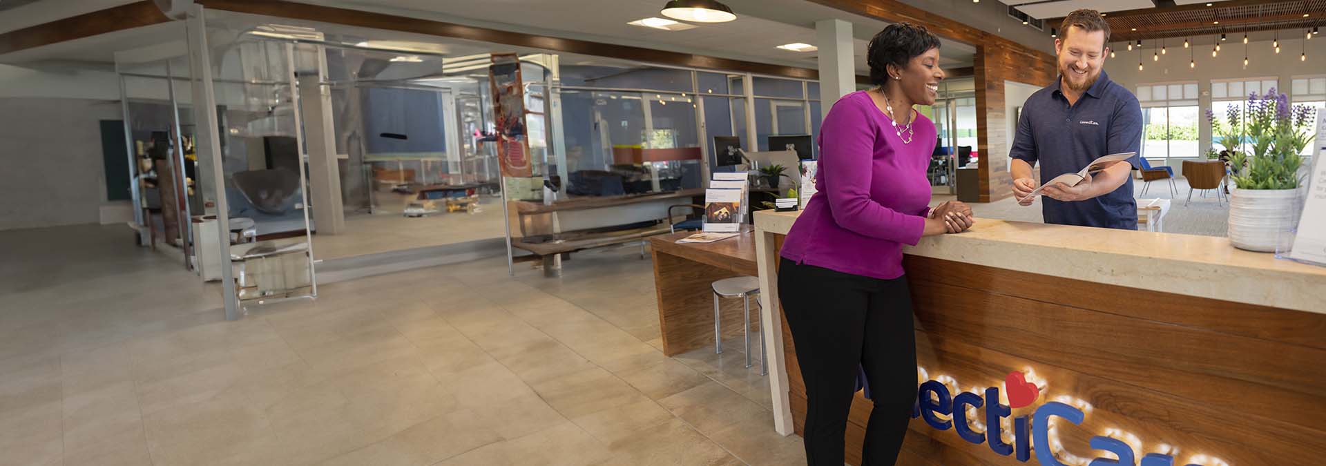 una recepcionista está con un cliente en una oficina de ConnectiCare