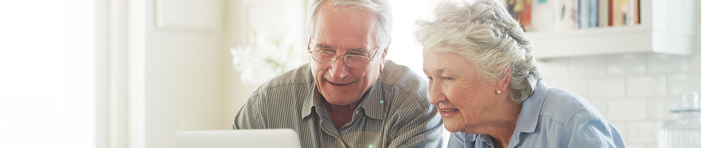 Fotografía de una pareja de ancianos usando una computadora portátil en casa